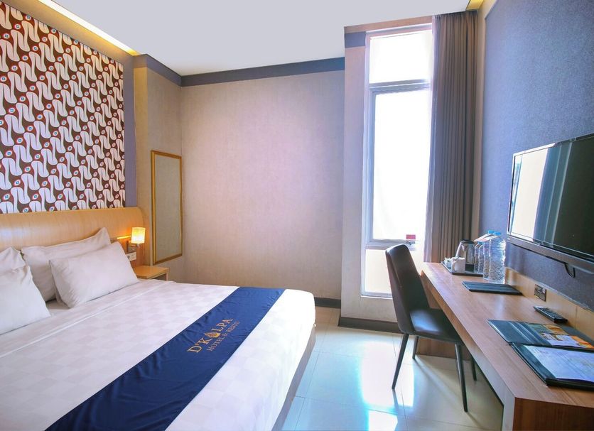 Dkayon Hotel Demangan Yogyakarta room with king bed, desk, chair, and tall window in Yogyakarta