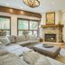 The Osprey at Beaver Creek living room with fireplace, sectional sofa, TV, and forest views
