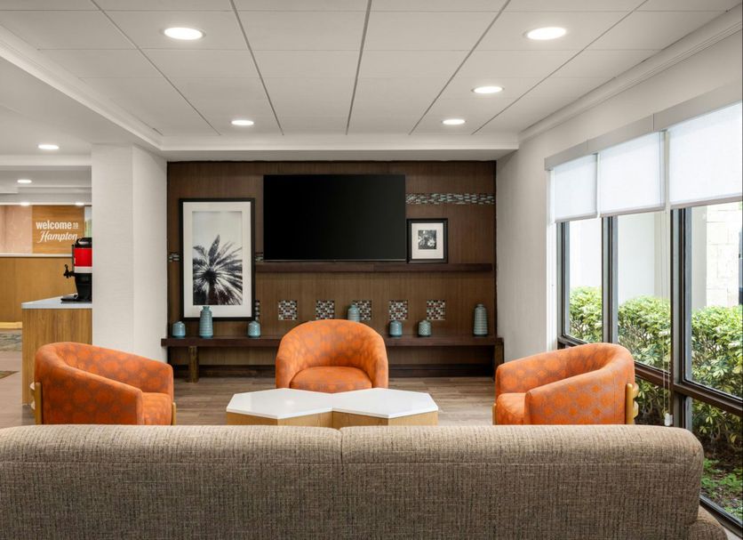 Hampton Inn Miami-Airport West lobby lounge in Doral with orange chairs, sofa, and large windows