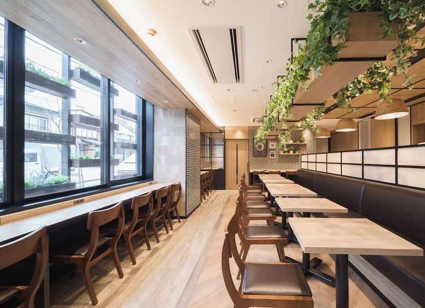 Super Hotel Hida Takayama dining area with long tables, window seating, and hanging greenery in Takayama