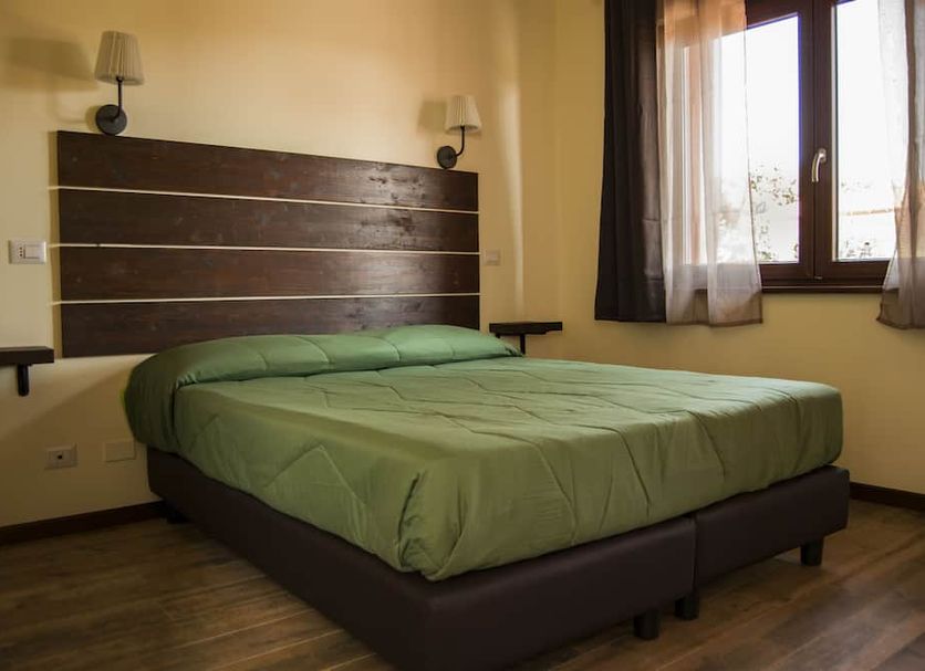 Sleep And Go Hotel Fiumicino guest room with double bed, wall lamps, and window