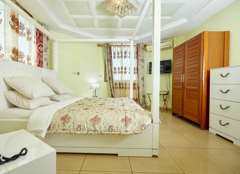 Felicia Hotel Yaounde in Yaoundé guest room with four-poster bed, wardrobe and tiled floor