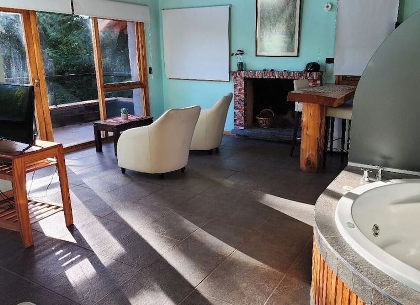 Casa Del Bosque Aparts in Villa La Angostura: lounge with fireplace, seating, and whirlpool tub
