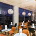 ibis Styles Versailles Guyancourt restaurant with orange chairs, round tables and hanging pendant lights