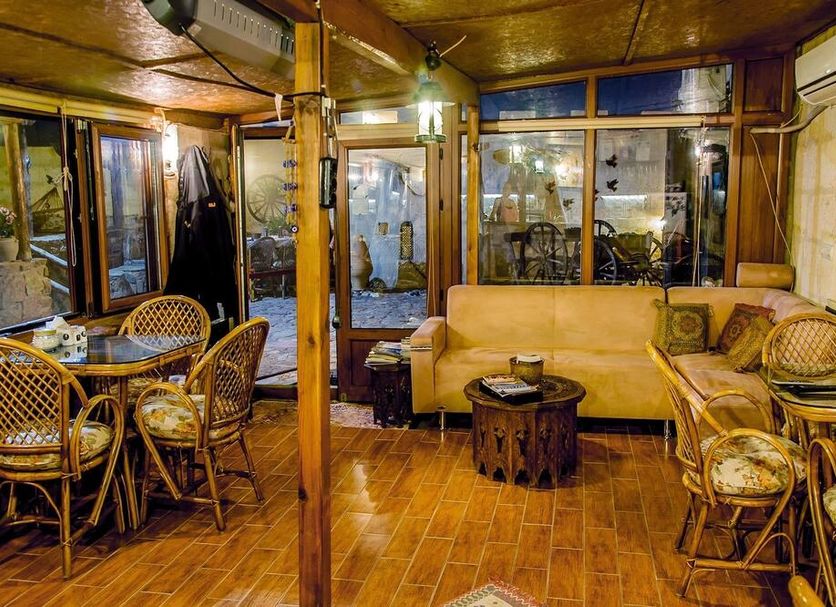 Adanos Konuk Evi in Avanos: cozy lounge with wicker chairs, beige sofa, and wood-paneled interior