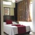 Hotel Playa Bonita in Mazatlán guest room with bed, red runner, wardrobe, and window curtains
