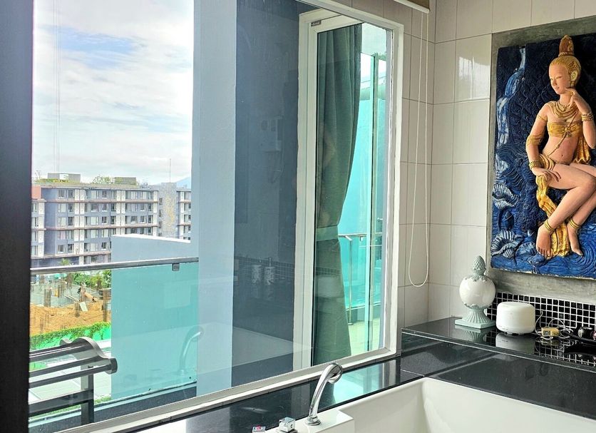 Am Surin Place bathroom with tub, balcony view, and wall art in Choeng Thale
