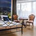 Royal Gdansk hotel room with wrought-iron bed, city skyline wall mural, and two chairs by window