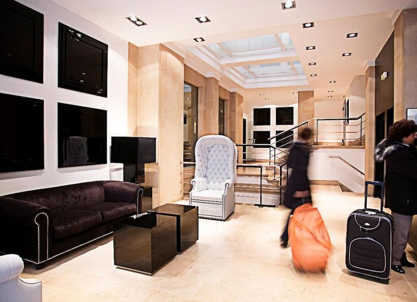Hotel Clarin Oviedo lobby with seating area, elevator and guests with luggage