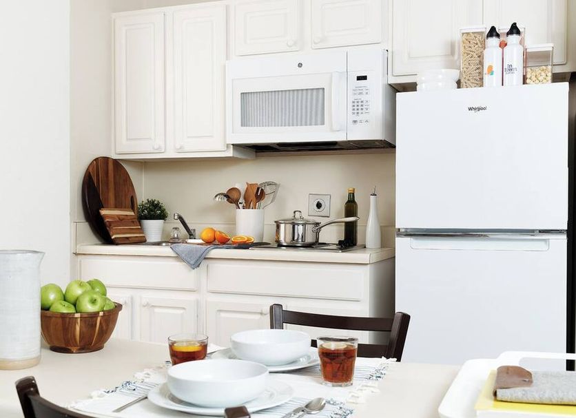 Intown Suites Extended Stay Prattville Al kitchen with white cabinets, fridge, microwave and dining table