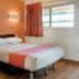 Motel 6 Mammoth Lakes room with queen bed, orange accent wall, and window with curtains