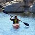 Gold Mountain Manor in Big Bear: kayaker paddling on a calm lake beside rocky shoreline