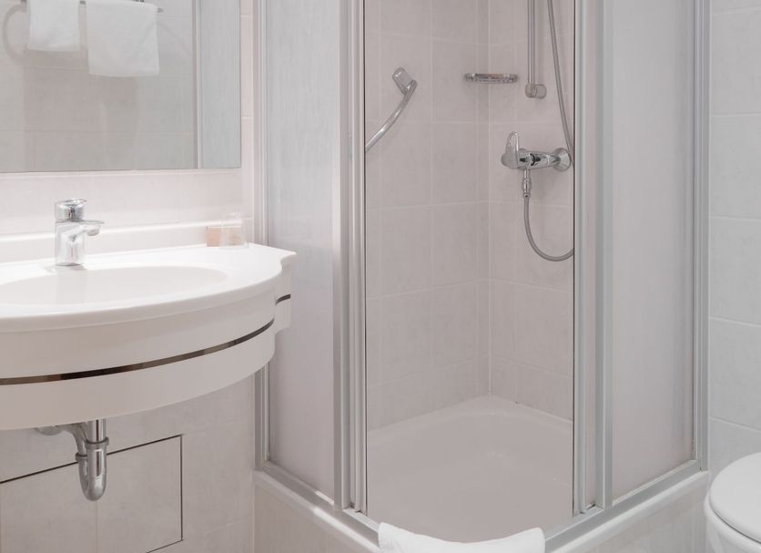 Hotel Van Walsum Rotterdam bathroom with walk-in shower, sink and toilet in a bright white tiled space