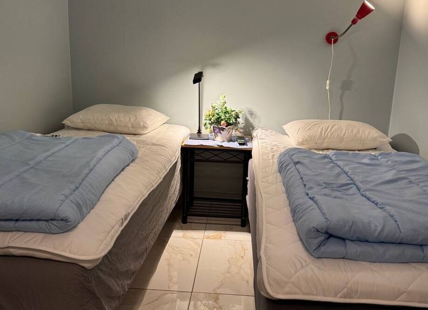 Svea Hostel Stockholm twin room with two single beds, nightstand, and wall lamps