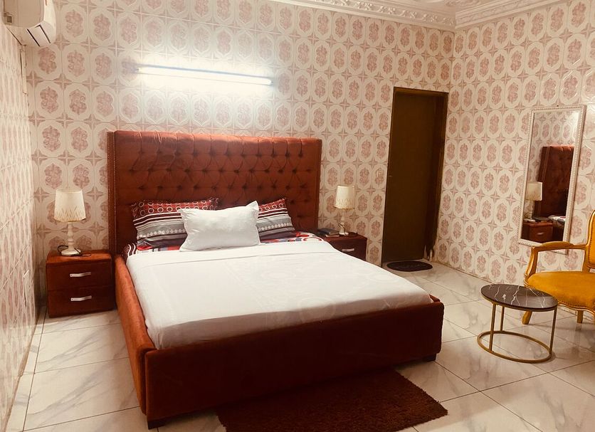 Residence Bethany Palace in Abidjan: bedroom with king bed, patterned wallpaper, mirrors and seating