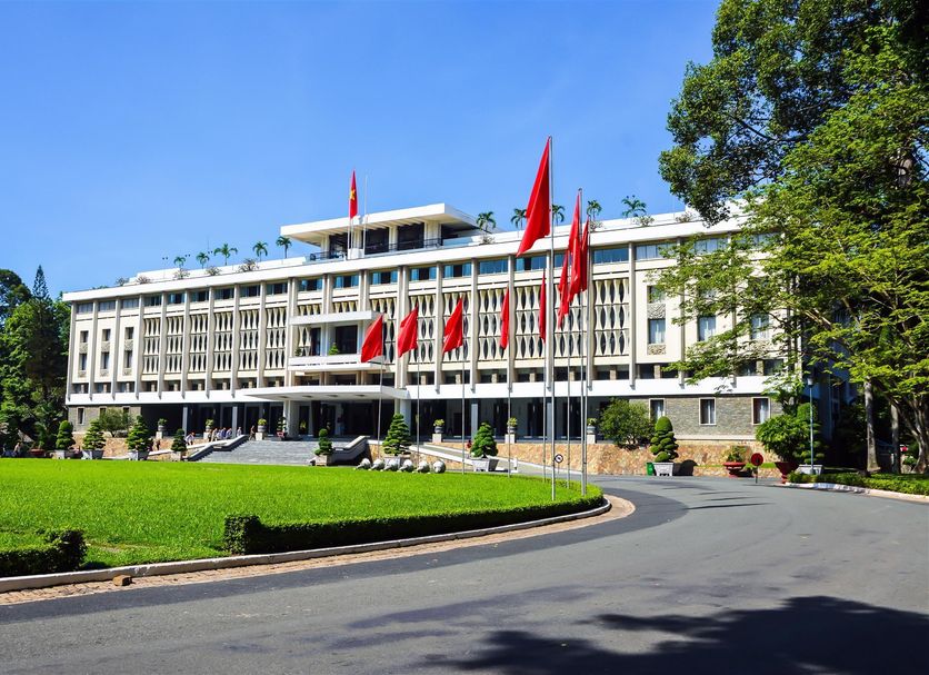 Funny Guesthouse in Ho Chi Minh City with white facade, red flags, and a landscaped lawn