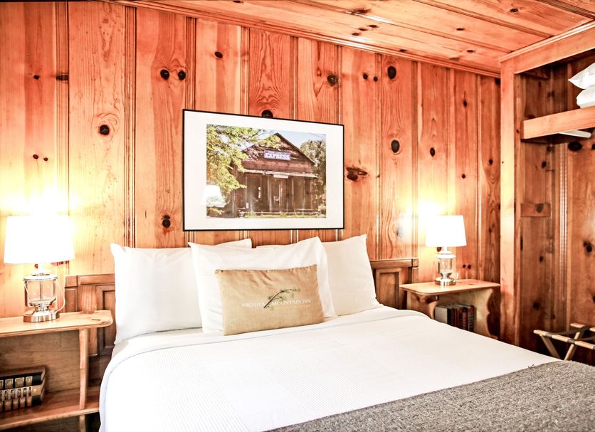 Sierra Mountain Inn in Grass Valley guest room with wood-paneled walls and a neatly made bed