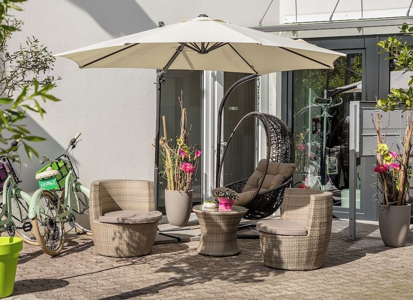 B&B Villa Verde in Salzburg patio with wicker chairs, umbrella, and glass doors