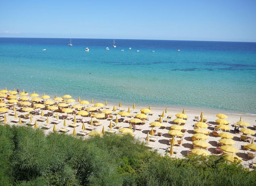 Th Costa Rei - Free Beach Resort in Costa Rei with rows of yellow umbrellas on a sandy beach and turquoise sea
