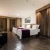 San Diego Suites Governador Valadares room with two beds, desk and dark wood flooring