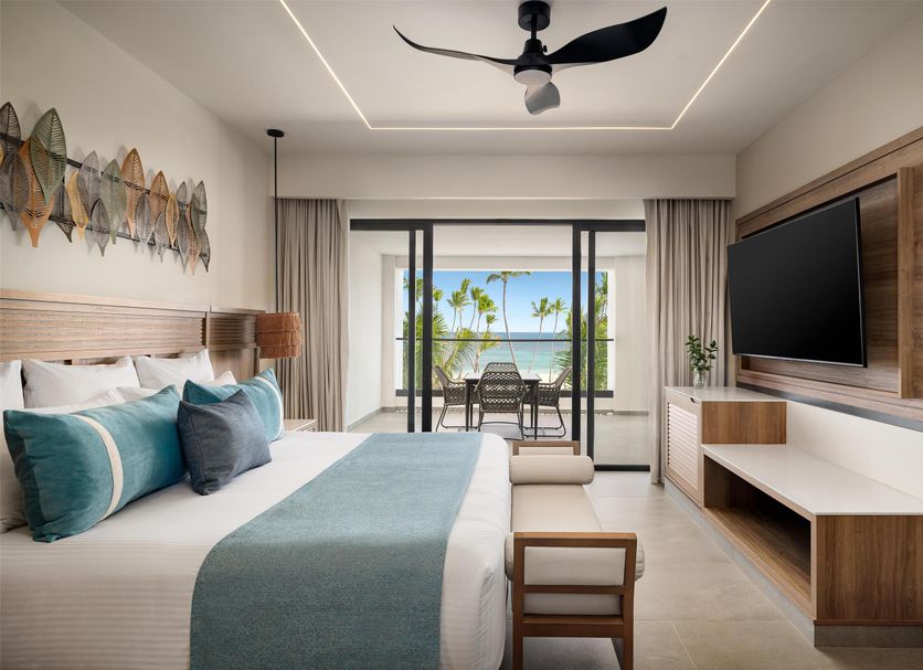 Secrets Tides Punta Cana room with ocean-view balcony, wall-mounted TV, and king bed in Uvero Alto