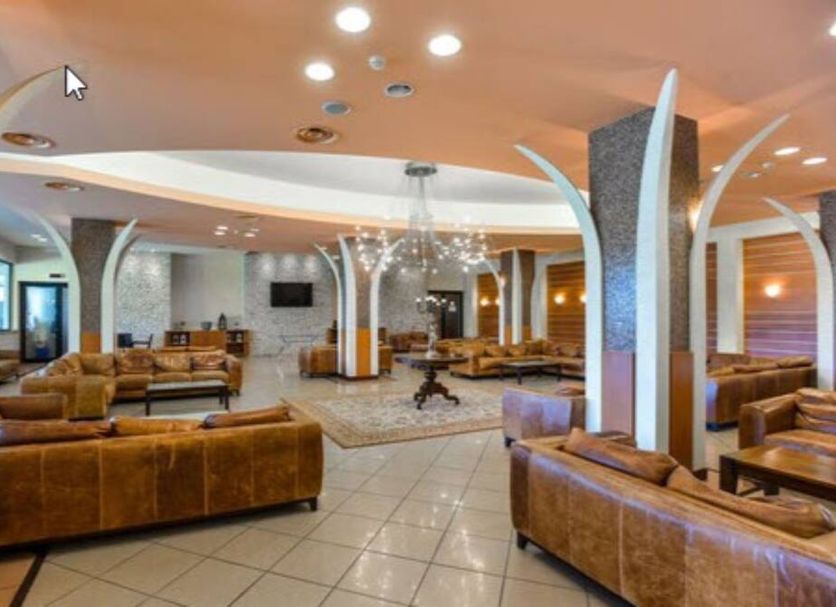Hotel Club Astor in Ugento lobby with leather sofas, tiled floor, and modern curved columns