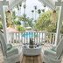 Hotel Casa Coson in Las Terrenas: wicker chairs on a wooden balcony with tropical garden and pool view