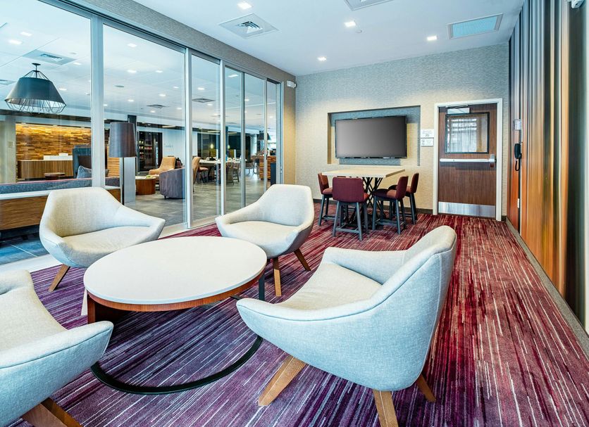 Courtyard by Marriott Toledo West lobby lounge with round tables, chairs, and floor-to-ceiling windows in Toledo
