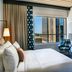 The Casso, Raleigh hotel room with city view, bed, desk and lounge chair by the window.