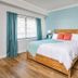 Surf House in Hampton: bright bedroom with turquoise accent wall, teal nightstand, and wood flooring.