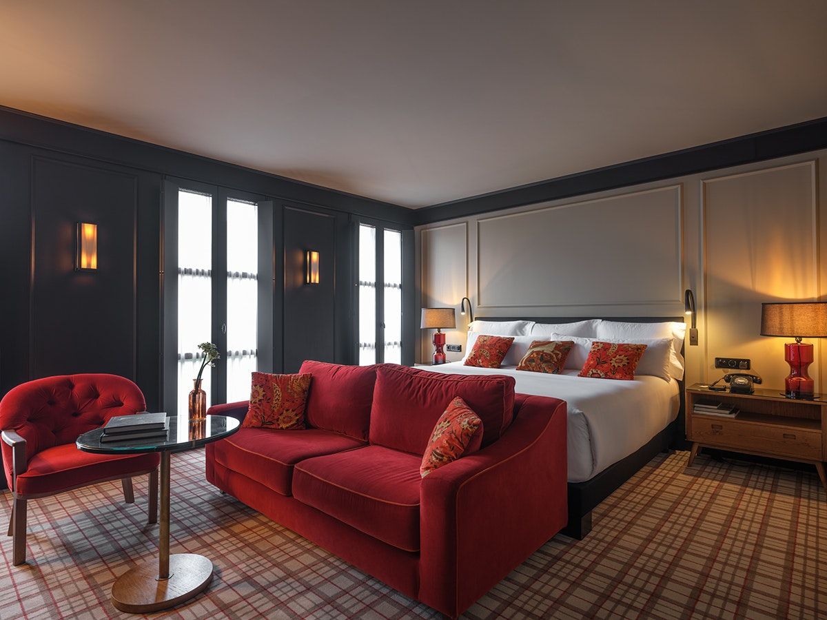 Wittmore Hotel Barcelona suite with red sofa, bed, and bedside lamps