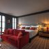 Wittmore Hotel Barcelona suite with red sofa, bed, and bedside lamps