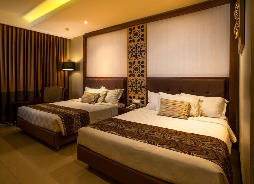 The Arnawa Hotel Pangandaran twin-bedded guest room with warm lighting and patterned headboard