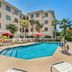 Best Western Plus Valdosta Hotel & Suites pool area with palm trees, red umbrellas and lounge chairs