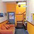 Abel's Central Backpackers reception area in Nelson with orange walls, sofa, and staircase