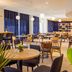 ibis Belfort Danjoutin dining area with round tables, chairs, pendant lights and blue curtains