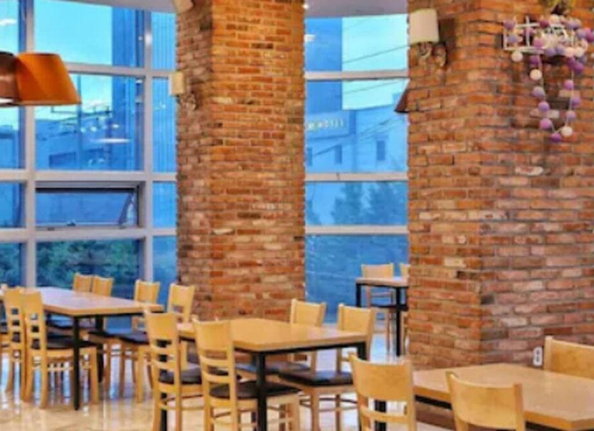 Rosana Hotel Seoul dining area with brick walls, large windows, and wooden tables and chairs