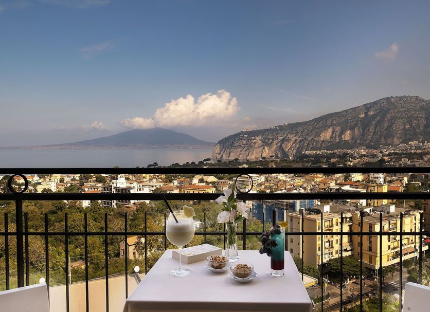 Hotel Cristina in Sorrento with balcony table overlooking sea, town, and distant mountains