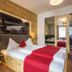 Hotel Kirchenwirt in Kaunertal: cozy wood-paneled guest room with double bed and red bed runner