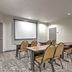 Meeting room at Candlewood Suites Houston (The Woodlands) By IHG with tables, chairs, and projector screen