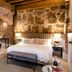 Sofraga Palacio in Ávila bedroom with freestanding tub, exposed brick arch, and stone wall