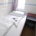 Garden Guest House in Hong Kong features a compact single bed beside a small bedside table and window.