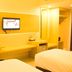 Horison Hotel Sukabumi room with two beds, desk, wall-mounted TV and open wardrobe