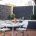 Hotel Hacienda Sydney patio with round table, white chairs, cactus plants and brick flooring