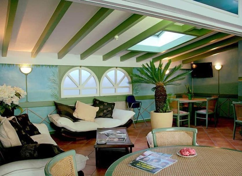 Hôtel du Port in Villeneuve lounge with skylight, arched windows, palm plant and seating area