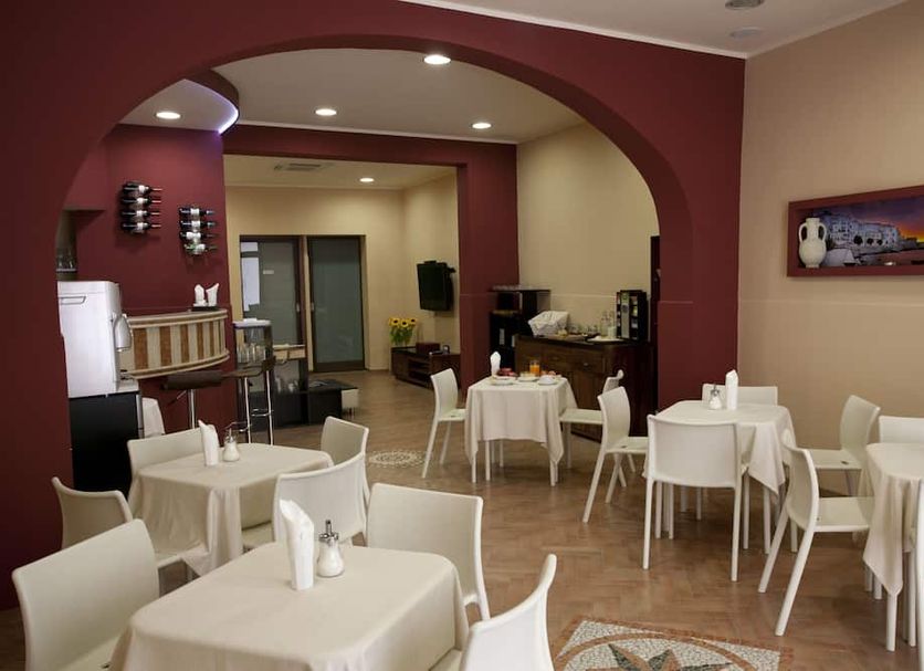 Residence Cortile Mercè dining room in Trapani with white tables and chairs under maroon arches