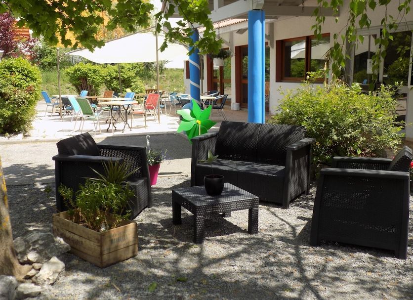 Nestor Hotel Gap et Restaurant patio with black seating, tables and shaded garden area in Gap