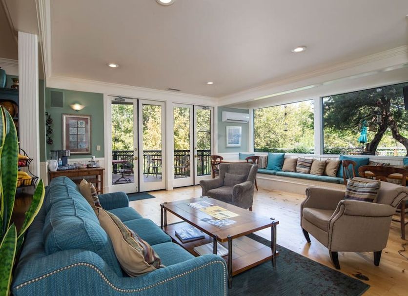 The Inn Above Oak Creek in Sedona: bright lounge with sofas, armchairs, and large windows overlooking trees.