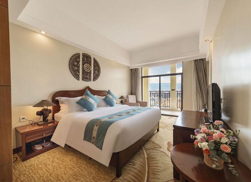 Jingland Exhibition Hotel in Xishuangbanna guest room with balcony view and king bed