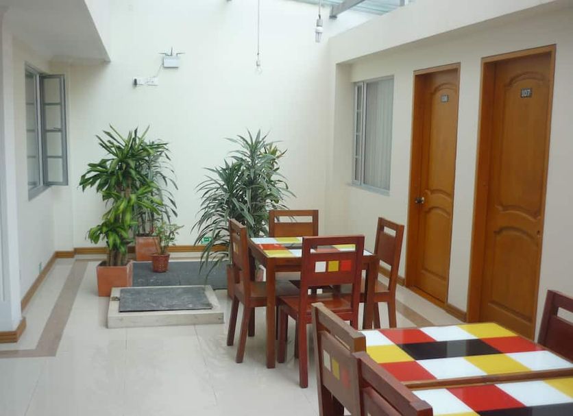 Hotel Casa La Riviera in Bogotá patio with dining tables, potted plants, and two wooden doors